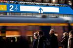 Passengers watch as a train pulls up to the platform. Above the train on the far wall, a digital display shows where the doors will be once the train starts, and indicates how full each section of the train is.