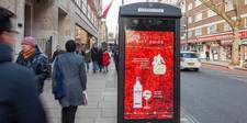 A digital display showing Clear Channel's Valentine's Day gift guide. The background is a bed of red roses, and the ads are for Marc Jacobs perfume and Gordon's Pink Gin.